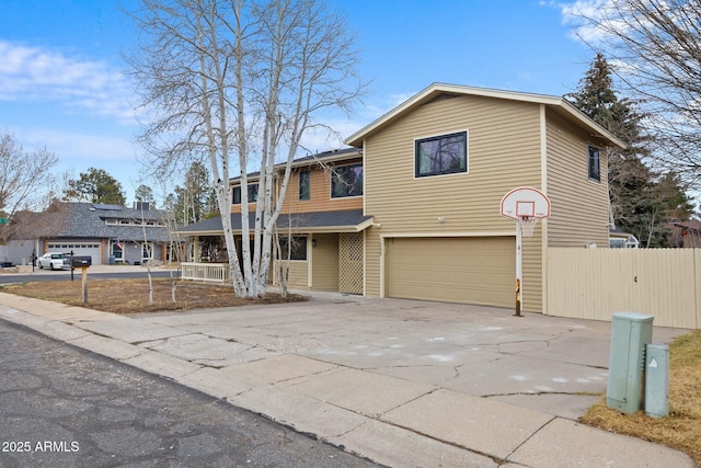 view of front of property featuring driveway, a garage, and fence