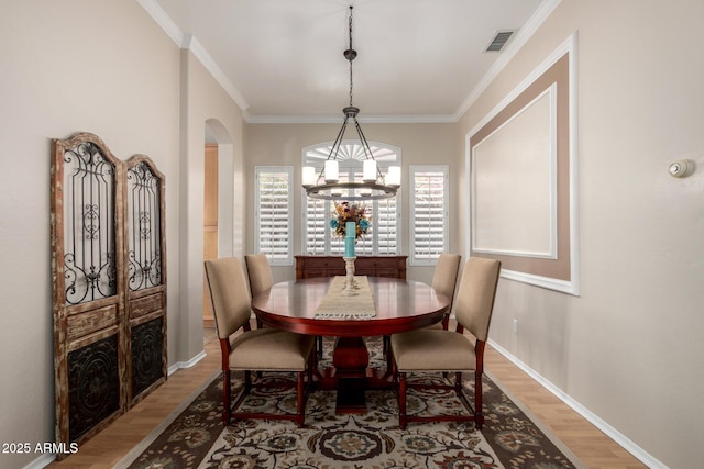 22232 N 48th St, Phoenix, AZ 85054 - dining area with arched walkways, a chandelier, wood finished floors, visible vents, and ornamental molding