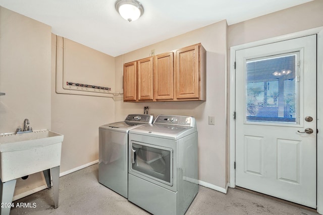 clothes washing area featuring separate washer and dryer and cabinets