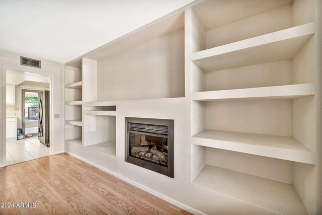 unfurnished living room featuring built in shelves and light hardwood / wood-style flooring