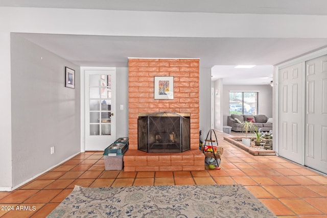 unfurnished living room with brick wall, a brick fireplace, and tile floors