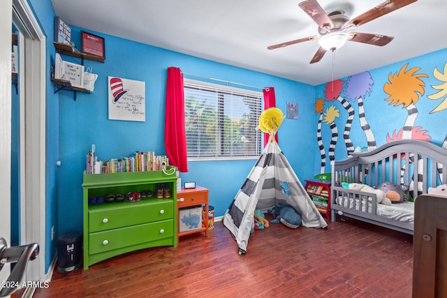 bedroom with dark hardwood / wood-style flooring, ceiling fan, and a nursery area