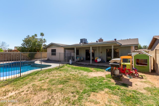 rear view of property with a fenced in pool, a lawn, and a patio