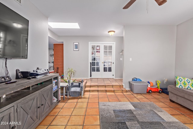 interior space featuring ceiling fan, light tile floors, french doors, and a skylight