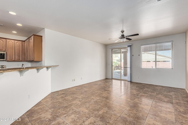 unfurnished living room with dark tile patterned flooring and ceiling fan