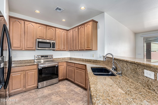 kitchen featuring light stone countertops, sink, kitchen peninsula, light tile patterned flooring, and appliances with stainless steel finishes