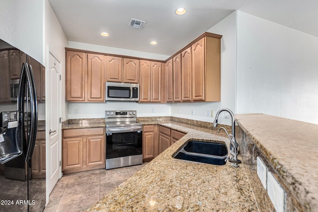 kitchen with light stone counters, sink, light tile patterned floors, and appliances with stainless steel finishes