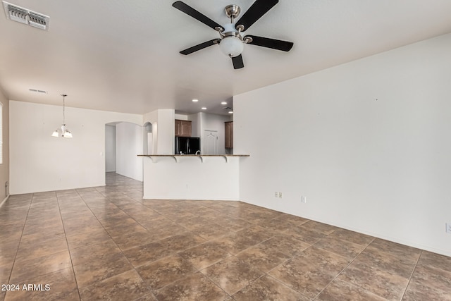 unfurnished living room with ceiling fan with notable chandelier