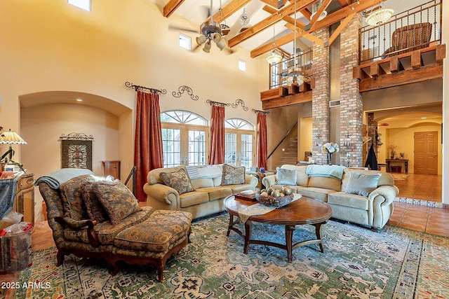 living room with a towering ceiling, decorative columns, ceiling fan, tile patterned floors, and beam ceiling