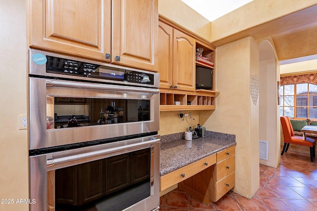 kitchen featuring stainless steel double oven, light brown cabinets, and light tile patterned floors