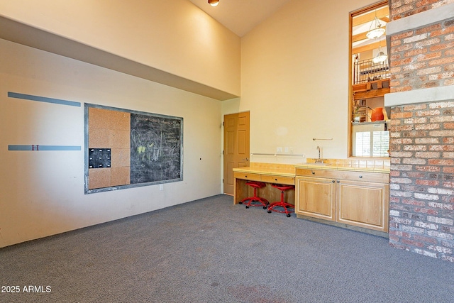 unfurnished office featuring a towering ceiling, sink, and dark carpet