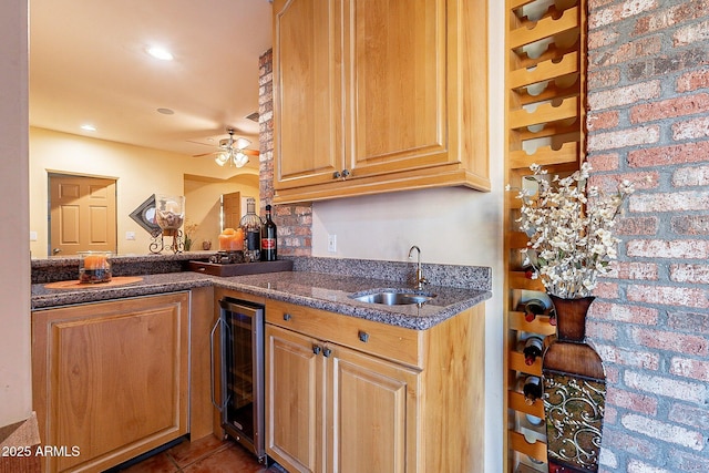 kitchen featuring sink, ceiling fan, brick wall, dark tile patterned flooring, and beverage cooler