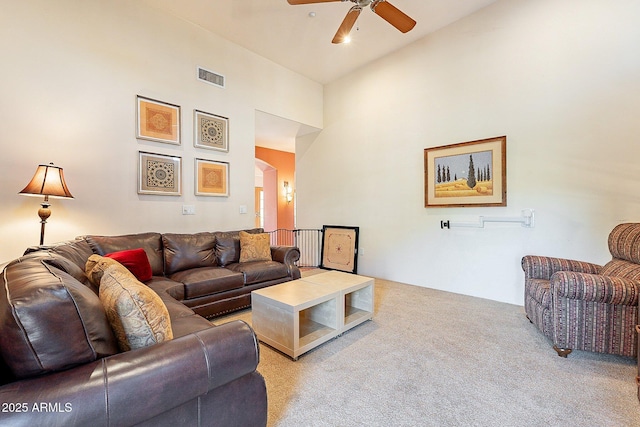 carpeted living room with ceiling fan and high vaulted ceiling