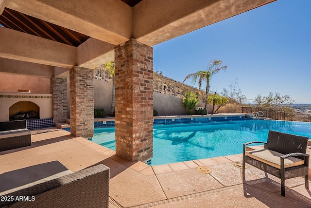 view of swimming pool with exterior fireplace and a patio