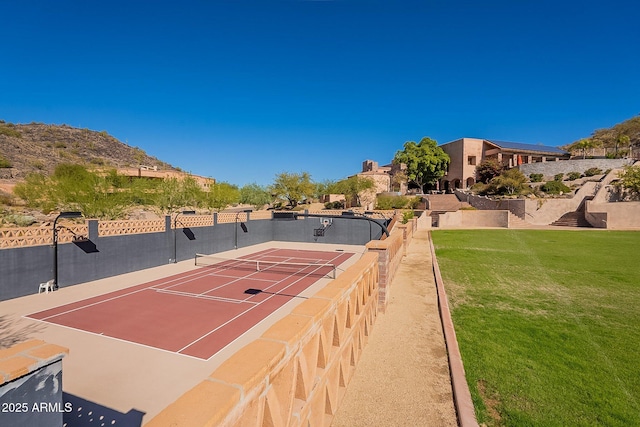 view of tennis court featuring a lawn