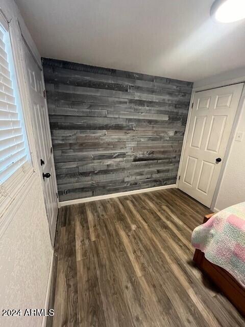 bedroom with wood walls and dark hardwood / wood-style floors