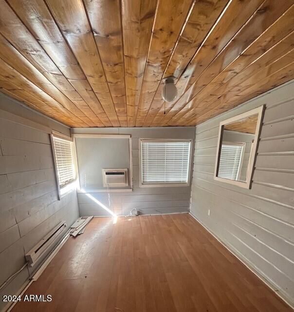 interior space with a wall mounted air conditioner, hardwood / wood-style floors, and wooden ceiling