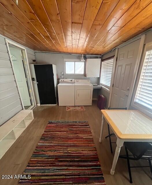 clothes washing area featuring washer and dryer, wooden ceiling, and light hardwood / wood-style flooring