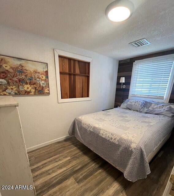 bedroom featuring a textured ceiling and dark hardwood / wood-style flooring