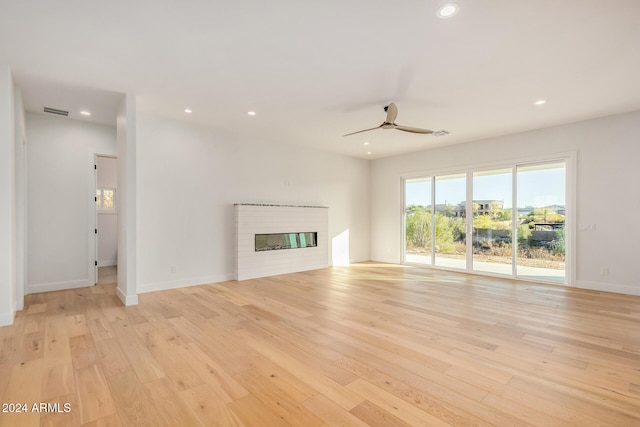 unfurnished living room with a fireplace, ceiling fan, and light hardwood / wood-style flooring