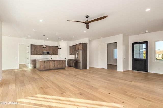 kitchen featuring pendant lighting, a center island with sink, stainless steel appliances, and light hardwood / wood-style flooring