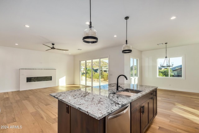 kitchen featuring hanging light fixtures, sink, stainless steel dishwasher, and light hardwood / wood-style floors