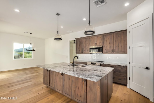 kitchen featuring sink, light wood-type flooring, stainless steel appliances, and a kitchen island with sink