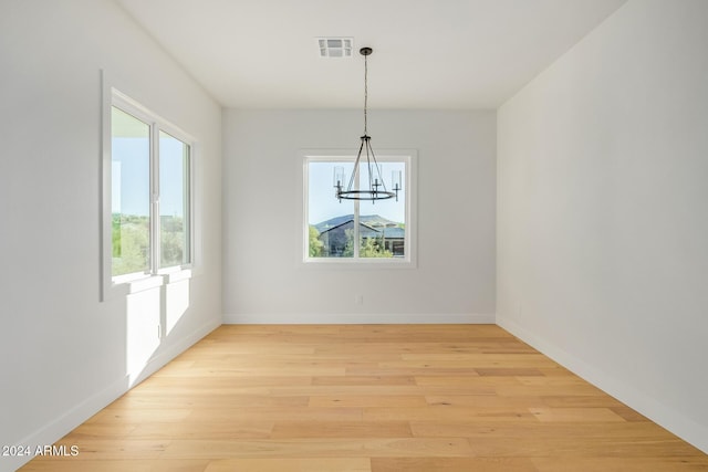 unfurnished dining area with light hardwood / wood-style floors and an inviting chandelier