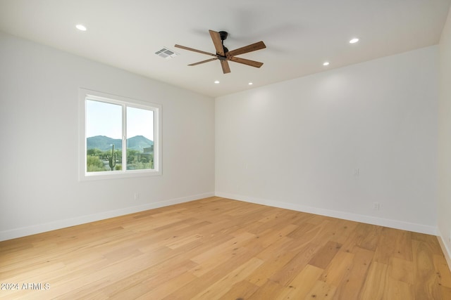 empty room featuring ceiling fan, light hardwood / wood-style floors, and a mountain view