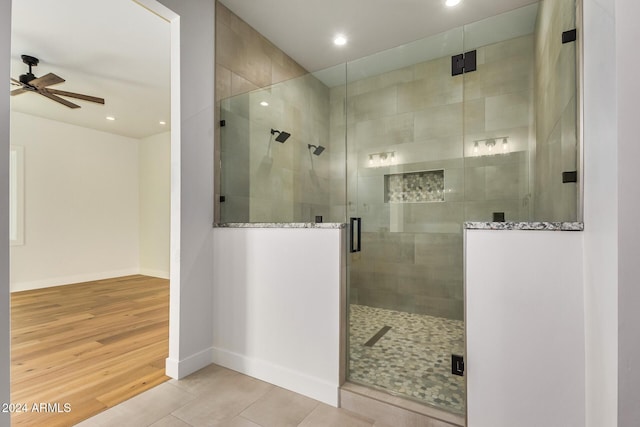 bathroom featuring hardwood / wood-style floors, ceiling fan, and a shower with shower door