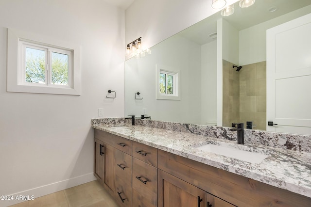 bathroom with tile patterned flooring, plenty of natural light, tiled shower, and vanity