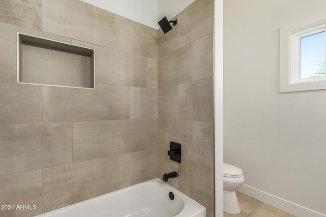 bathroom with toilet, tile patterned flooring, and tiled shower / bath