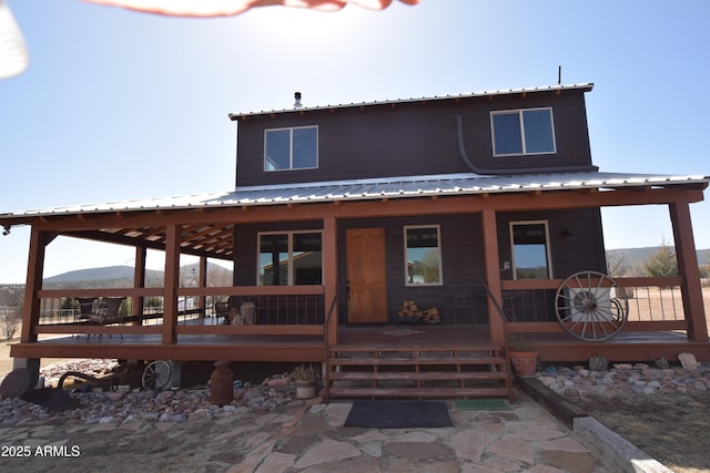 rear view of property featuring a porch and metal roof