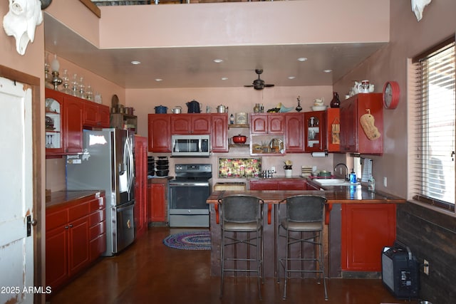 kitchen featuring a ceiling fan, a peninsula, open shelves, appliances with stainless steel finishes, and a kitchen bar