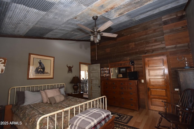 bedroom with lofted ceiling, wood finished floors, and wood walls