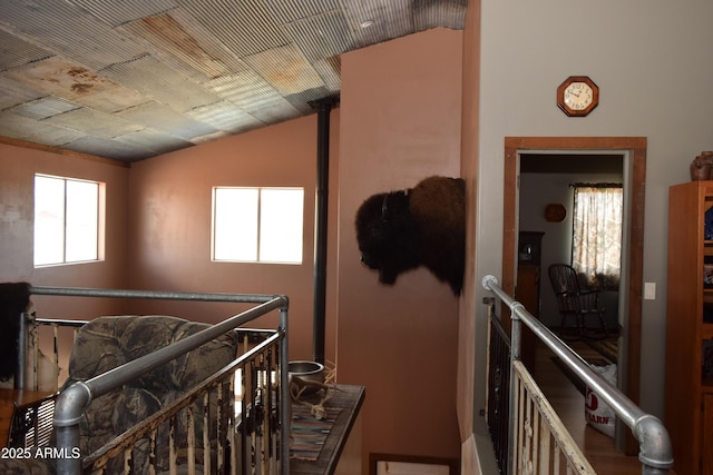 hallway with lofted ceiling and an upstairs landing