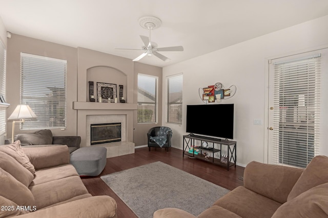 living room featuring baseboards, a ceiling fan, dark wood finished floors, and a fireplace