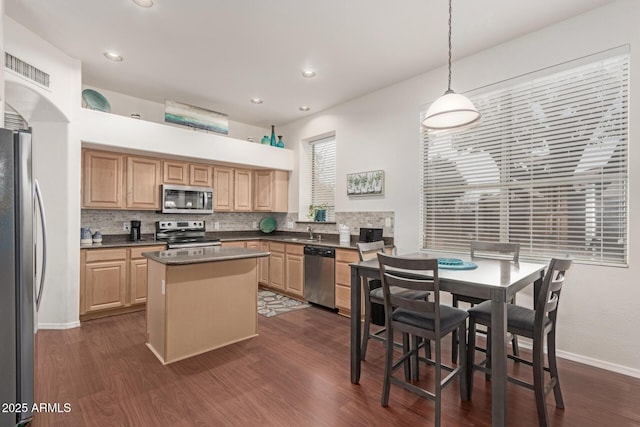 kitchen with dark wood-type flooring, a center island, backsplash, and stainless steel appliances