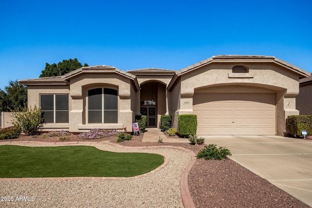 view of front facade with stucco siding, driveway, a tile roof, and a garage