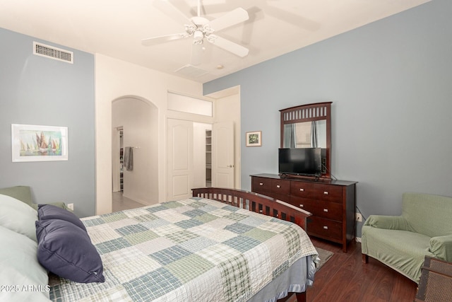 bedroom featuring visible vents, arched walkways, a ceiling fan, and dark wood-style flooring