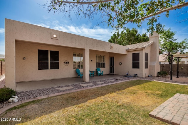 back of house featuring stucco siding, a lawn, a tile roof, fence, and a patio area