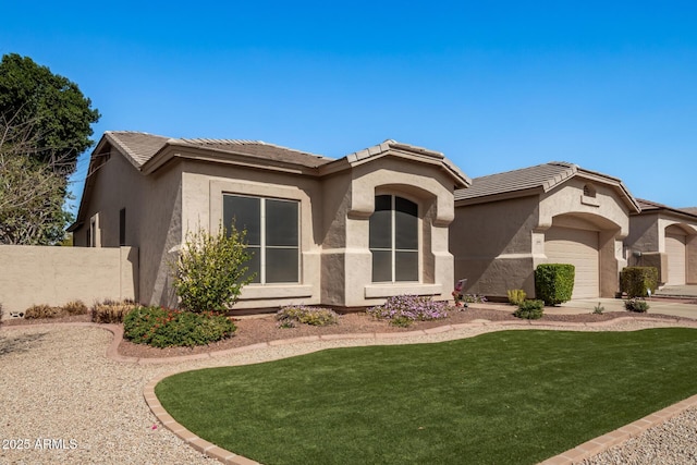 view of front of home featuring stucco siding, a front lawn, an attached garage, and a tile roof