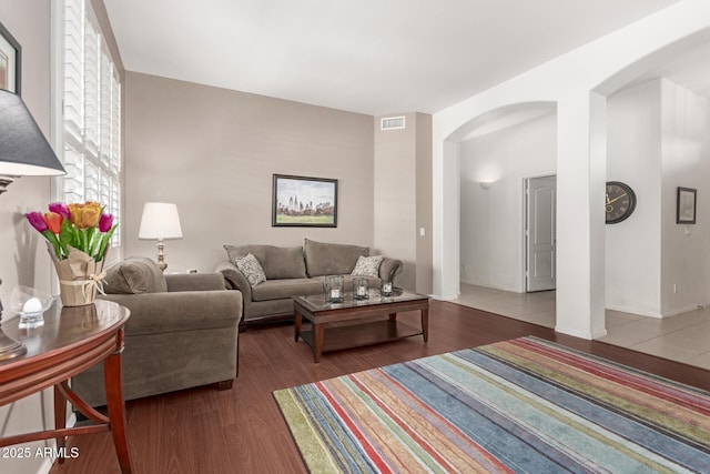 living area with arched walkways, visible vents, and wood finished floors