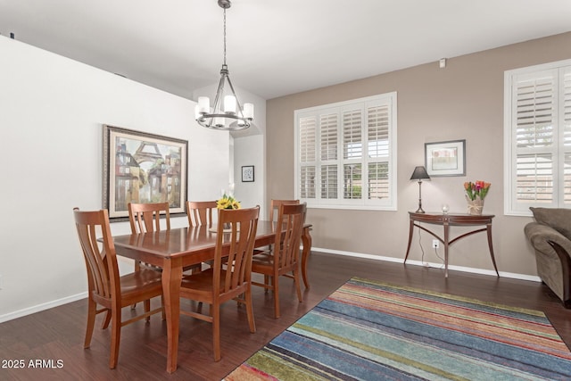 dining space with baseboards, a notable chandelier, and wood finished floors