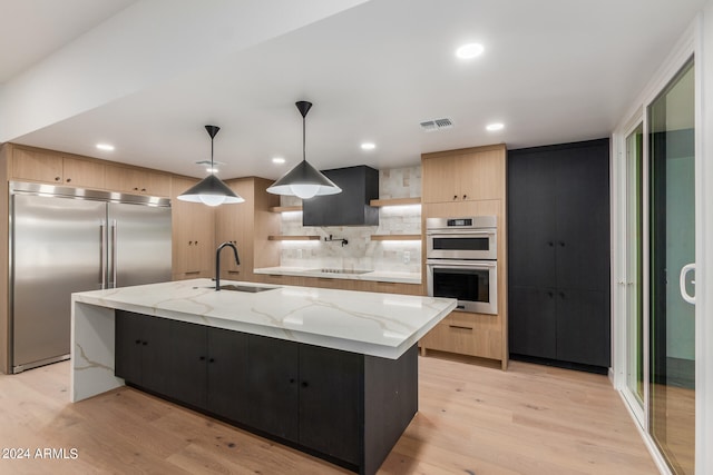 kitchen with light brown cabinets, tasteful backsplash, light hardwood / wood-style floors, sink, and stainless steel appliances