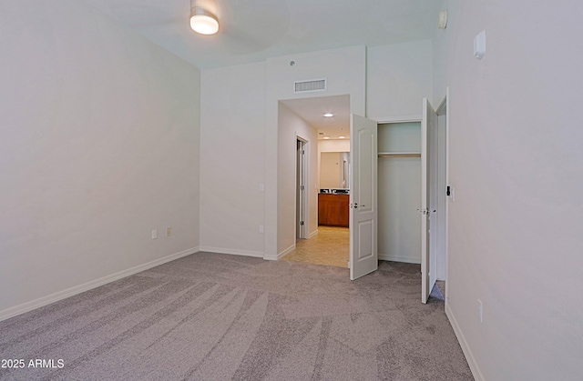 unfurnished bedroom with light carpet, baseboards, and ensuite bathroom