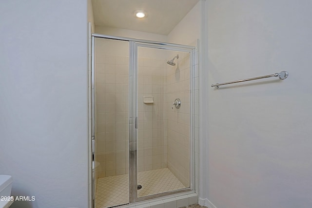 bathroom with toilet, a shower stall, and baseboards