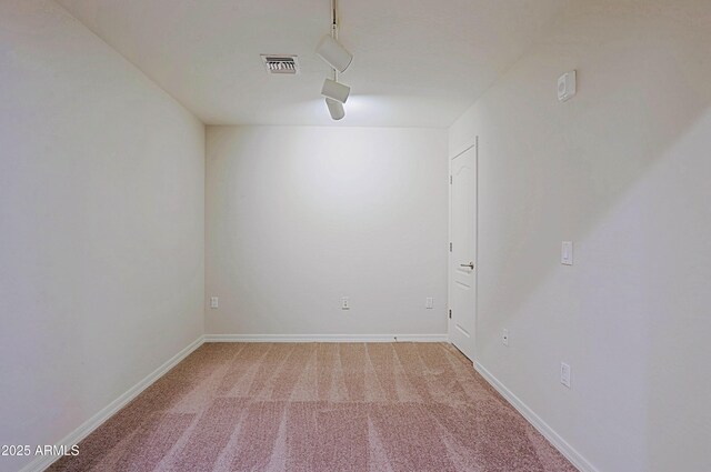 spare room featuring carpet, rail lighting, and baseboards