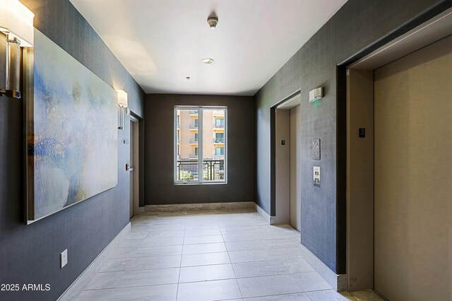 hall with elevator and light tile patterned floors