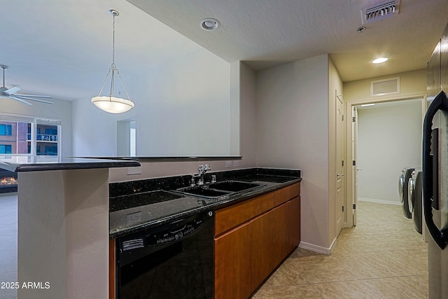 kitchen with independent washer and dryer, a sink, black dishwasher, brown cabinets, and light tile patterned flooring